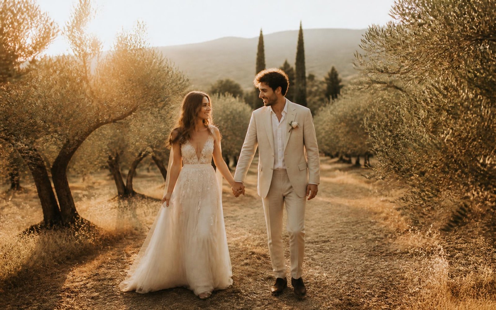 Amara and Julian walking hand in hand through a sunlit olive grove